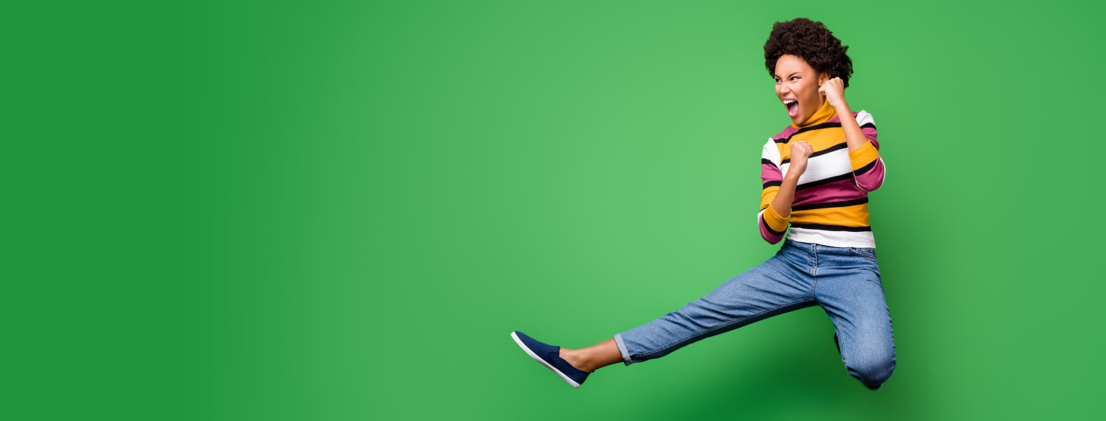 Woman jump-kicking on green background