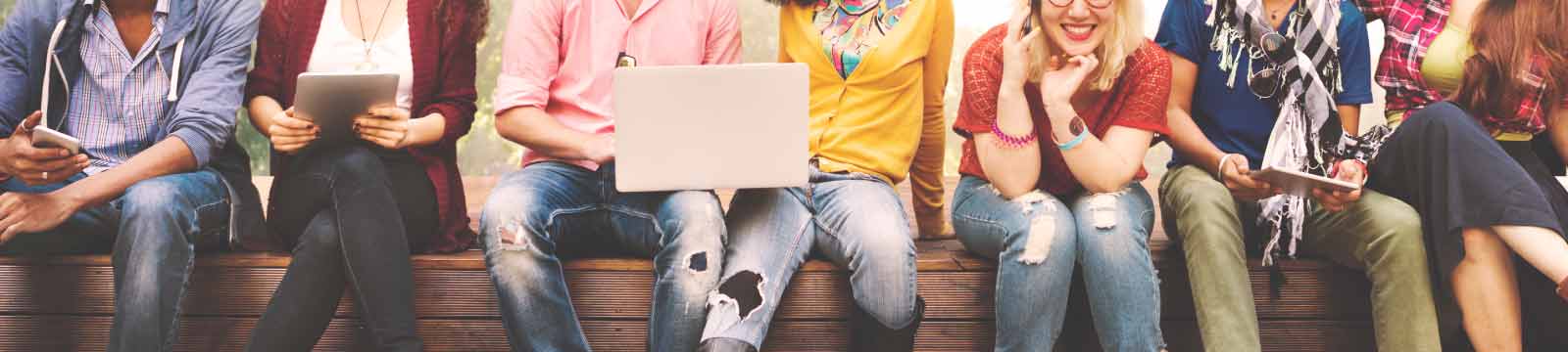 Teenagers sitting on wall with mobile devices